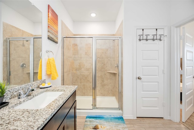 bathroom with a shower with shower door, wood-type flooring, and vanity