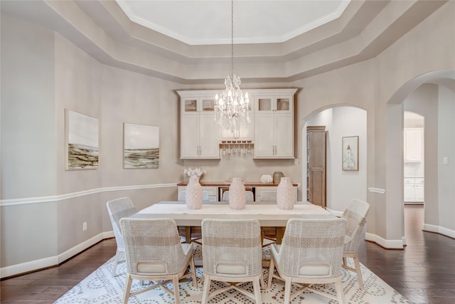 dining room with a raised ceiling, crown molding, a chandelier, and dark hardwood / wood-style floors