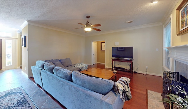 living room with a textured ceiling, hardwood / wood-style flooring, ceiling fan, and crown molding