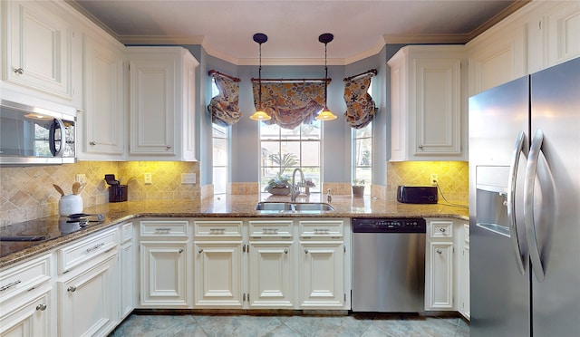 kitchen with pendant lighting, white cabinets, sink, appliances with stainless steel finishes, and kitchen peninsula