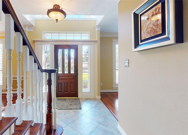 foyer entrance featuring a textured ceiling, a healthy amount of sunlight, light wood-type flooring, and ornamental molding