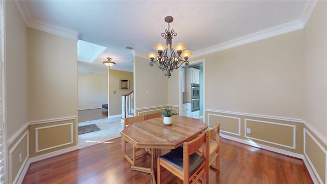 dining space featuring a chandelier, wood-type flooring, and crown molding