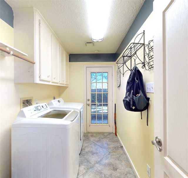 laundry area featuring light tile patterned flooring, cabinets, a textured ceiling, and washing machine and clothes dryer