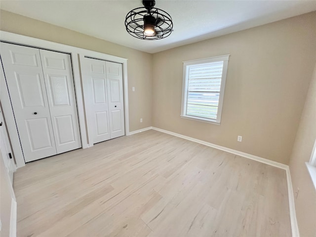 unfurnished bedroom with light wood-type flooring and two closets