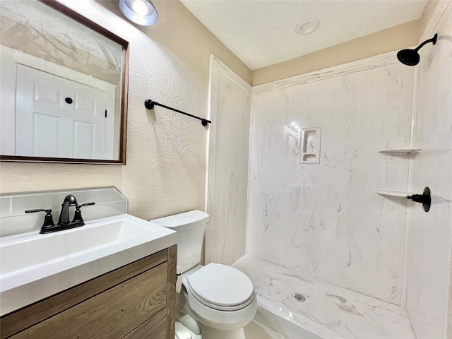 bathroom with a shower, vanity, and toilet