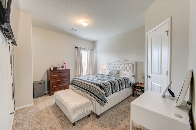 bedroom with a textured ceiling and light carpet