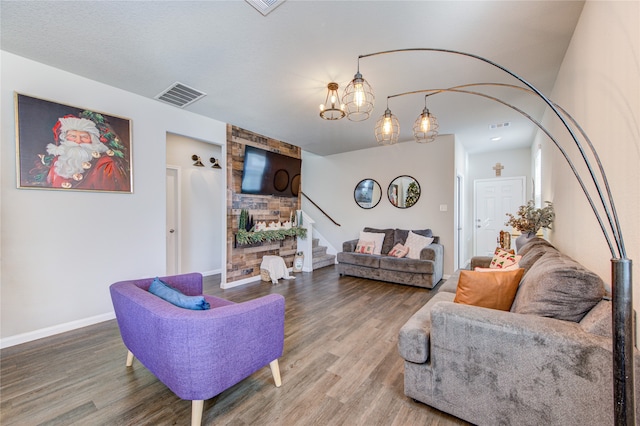 living room with hardwood / wood-style floors, a large fireplace, and an inviting chandelier