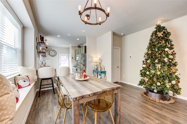 dining area with a textured ceiling, an inviting chandelier, plenty of natural light, and dark wood-type flooring