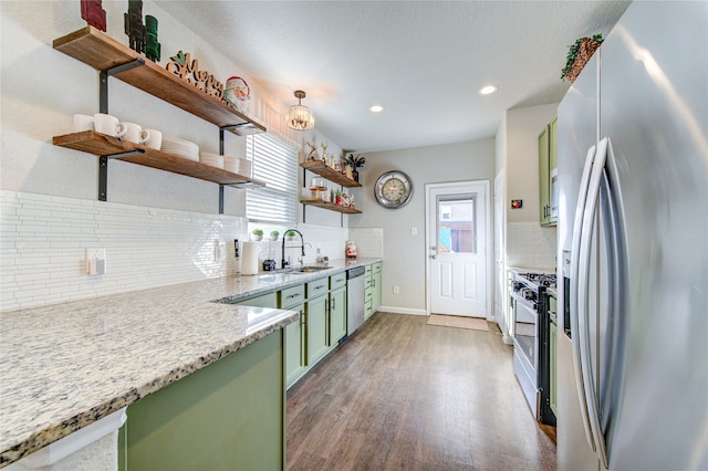 kitchen featuring hardwood / wood-style floors, backsplash, sink, green cabinetry, and appliances with stainless steel finishes