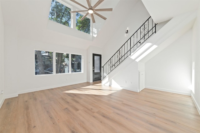 unfurnished living room featuring a towering ceiling, light hardwood / wood-style flooring, and a wealth of natural light