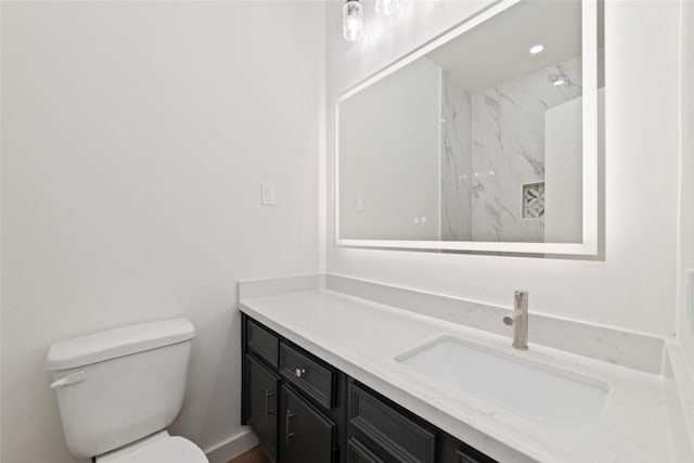 bathroom featuring tiled shower, vanity, and toilet