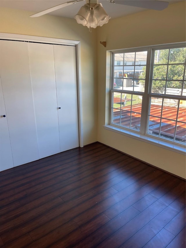 unfurnished bedroom featuring ceiling fan, a closet, and dark wood-type flooring