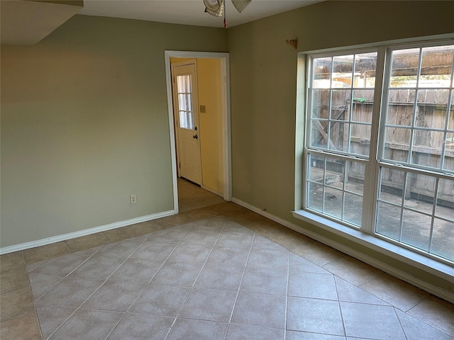 tiled empty room featuring a wealth of natural light and ceiling fan