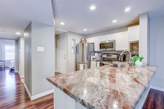 kitchen with kitchen peninsula, stainless steel appliances, white cabinets, and tasteful backsplash