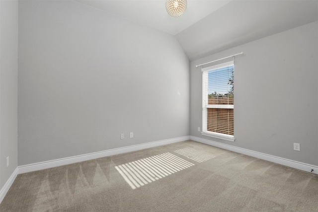 carpeted empty room with vaulted ceiling