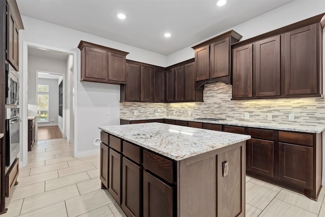 kitchen with dark brown cabinets, light stone countertops, and stainless steel appliances