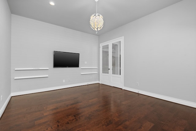 unfurnished living room featuring hardwood / wood-style flooring, a notable chandelier, and french doors