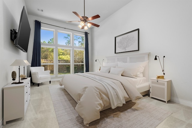 bedroom with ceiling fan, light colored carpet, and multiple windows