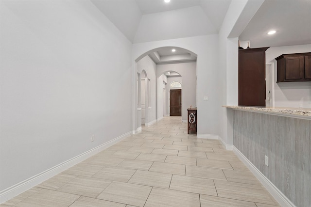 hallway with a tray ceiling and vaulted ceiling