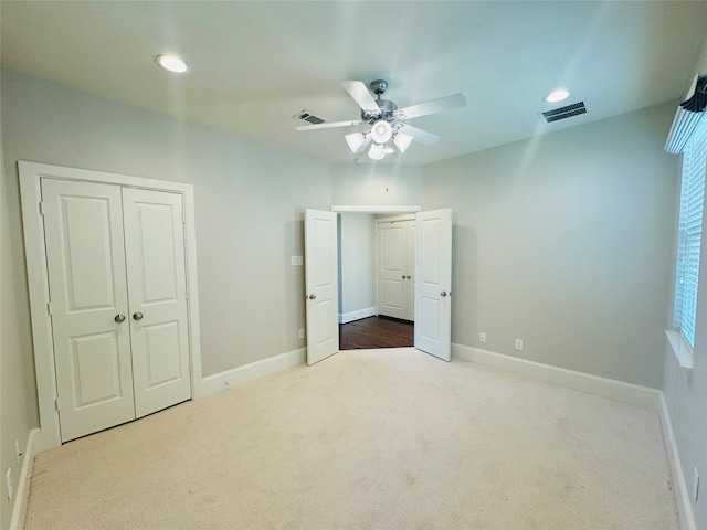 unfurnished bedroom featuring a closet, light colored carpet, and ceiling fan