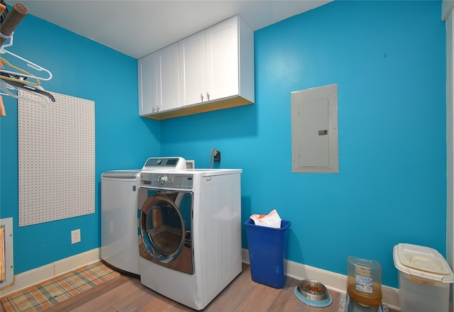 washroom featuring cabinets, light wood-type flooring, electric panel, and washing machine and clothes dryer