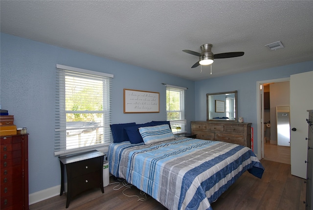 bedroom with a textured ceiling, ceiling fan, dark wood-type flooring, and multiple windows