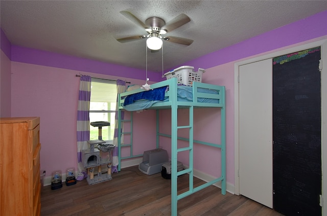 unfurnished bedroom featuring ceiling fan, a closet, wood-type flooring, and a textured ceiling