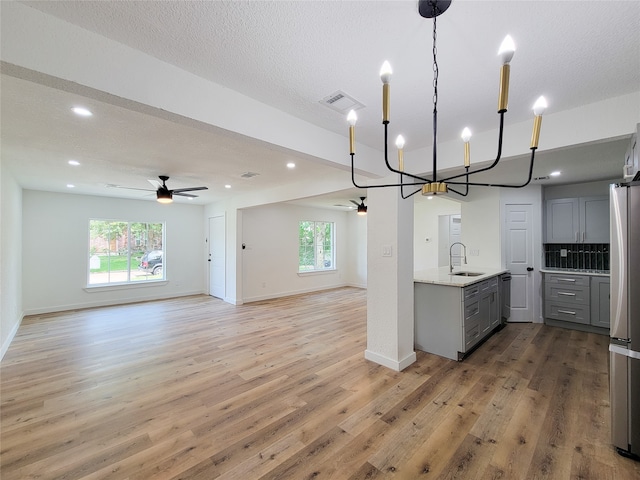 kitchen with gray cabinetry, plenty of natural light, ceiling fan with notable chandelier, and sink