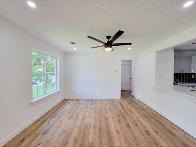 unfurnished living room with ceiling fan, light hardwood / wood-style flooring, and a textured ceiling