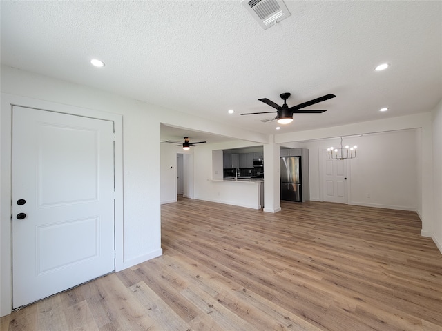 unfurnished living room with a textured ceiling, light hardwood / wood-style floors, and ceiling fan with notable chandelier