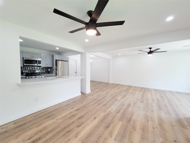 unfurnished living room featuring ceiling fan, light wood-type flooring, and sink