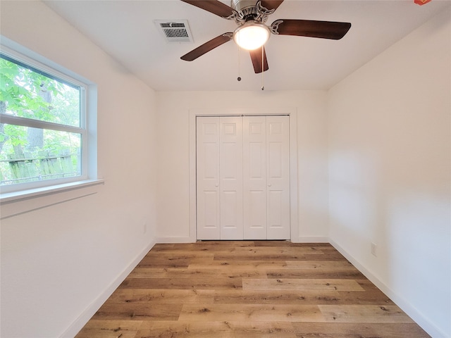 unfurnished bedroom featuring ceiling fan, light hardwood / wood-style floors, and a closet