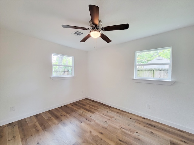 empty room featuring plenty of natural light, ceiling fan, and light hardwood / wood-style flooring