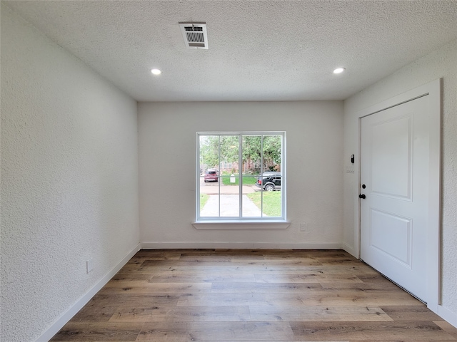 empty room with light hardwood / wood-style floors and a textured ceiling