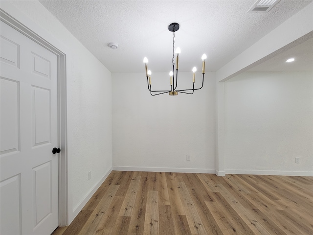 unfurnished dining area featuring a chandelier, a textured ceiling, and light hardwood / wood-style flooring