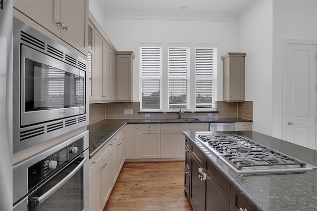 kitchen featuring dark stone counters, sink, light hardwood / wood-style flooring, decorative backsplash, and appliances with stainless steel finishes