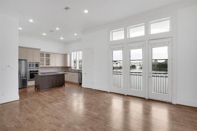 kitchen with appliances with stainless steel finishes, dark wood-type flooring, a kitchen island, and a healthy amount of sunlight