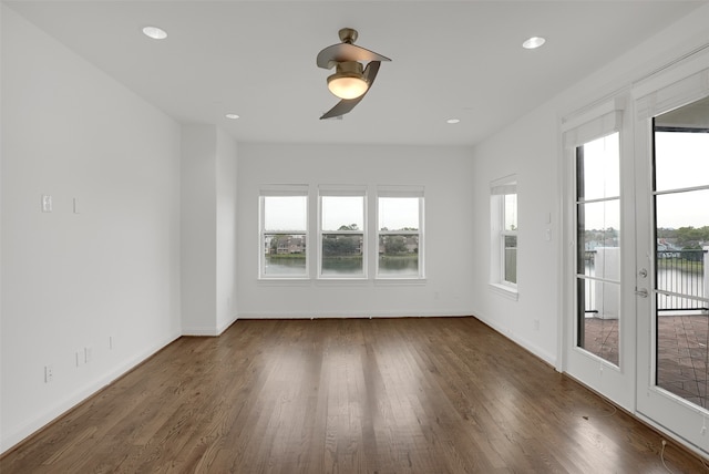 empty room with a wealth of natural light, dark wood-type flooring, and ceiling fan