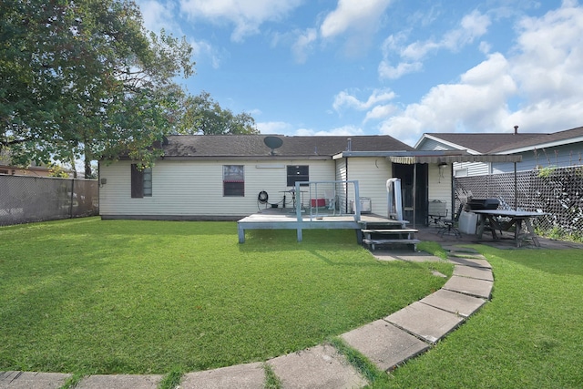 back of property with a deck and a yard