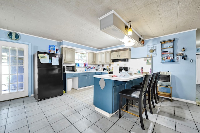 kitchen with stainless steel microwave, black refrigerator, light tile patterned flooring, a kitchen bar, and heating unit