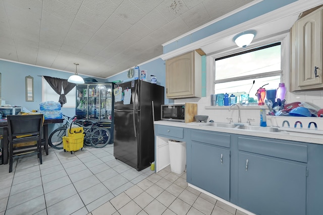 kitchen with sink, hanging light fixtures, black fridge, crown molding, and light tile patterned flooring