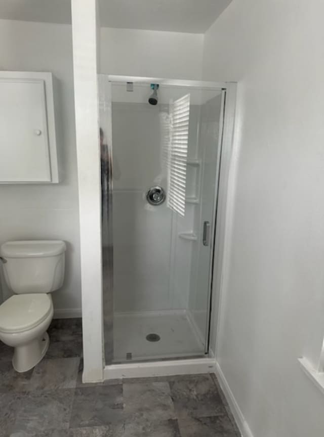 full bathroom featuring baseboards, a stall shower, and toilet