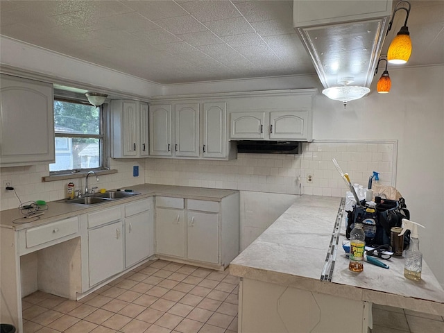 kitchen featuring a sink, light tile patterned floors, backsplash, and light countertops