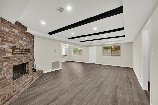 unfurnished living room featuring a fireplace, dark hardwood / wood-style floors, beamed ceiling, and a notable chandelier