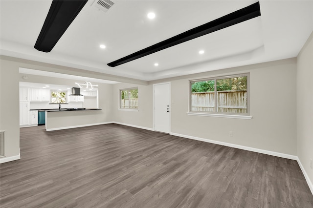 unfurnished living room with beamed ceiling, dark hardwood / wood-style flooring, and sink