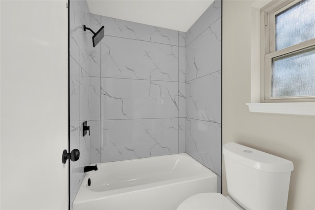 bathroom featuring tiled shower / bath combo and toilet