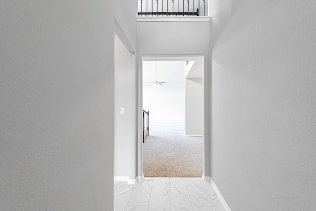 hallway featuring light carpet and a high ceiling