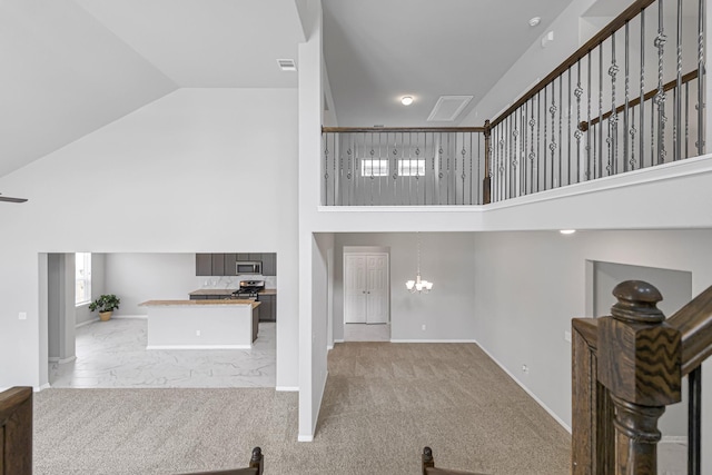 interior space featuring light carpet, a notable chandelier, and high vaulted ceiling