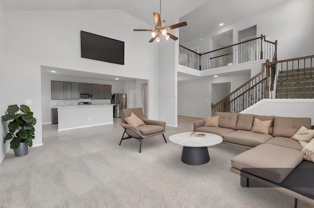 living room with a towering ceiling, light colored carpet, and ceiling fan