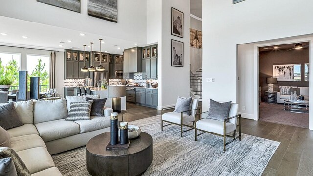 living room featuring a towering ceiling and dark wood-type flooring